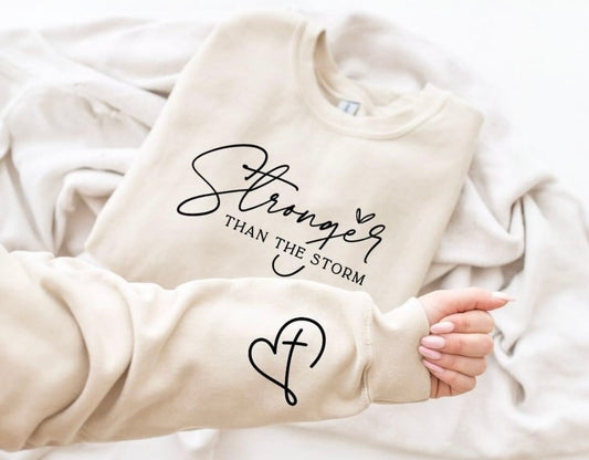 STRONGER THAN THE STORM WITH HEART/CROSS SLEEVE SALE SWEATSHIRT